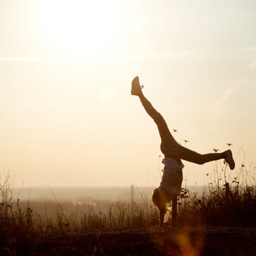 Young girl doing a handstand at sunset